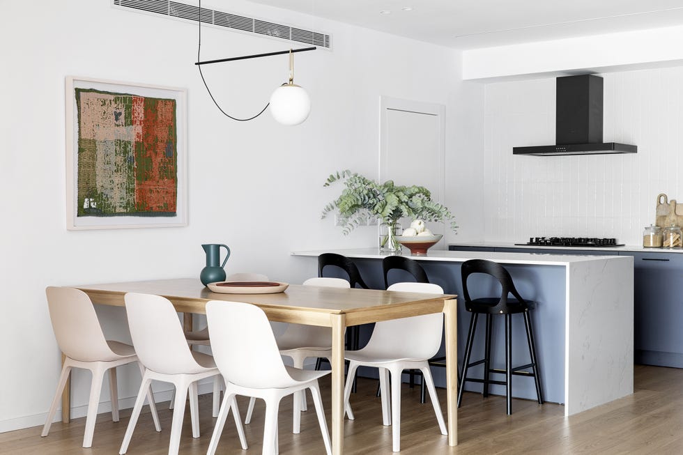 cocina abierta con barra y office con mesa de madera y sillas blancas