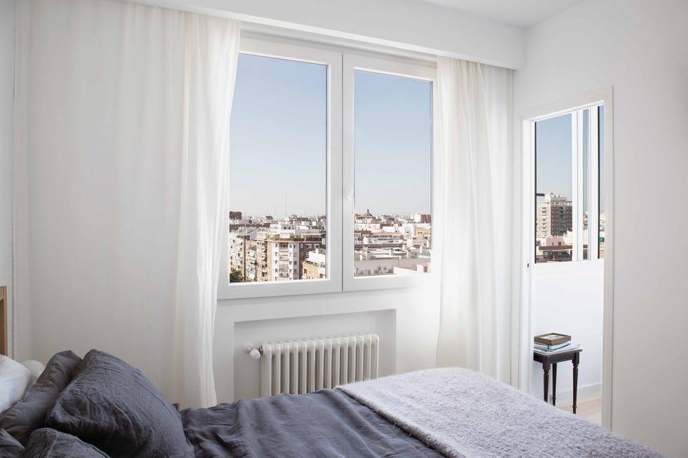 Dormitorio decorado en blanco con vistas a la ciudad
