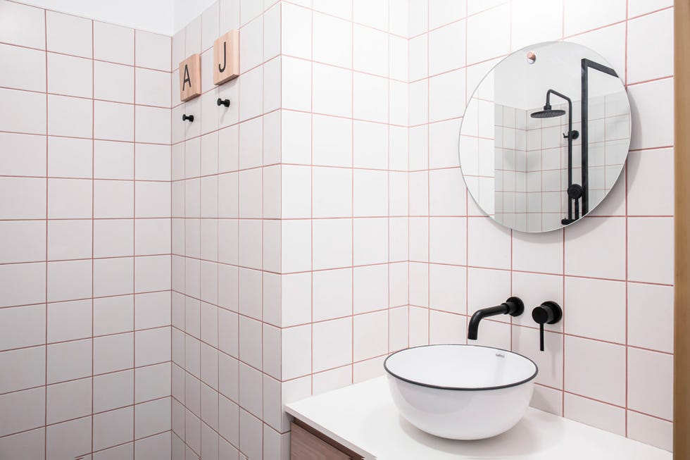Baño con azulejos blancos y juntas rojas