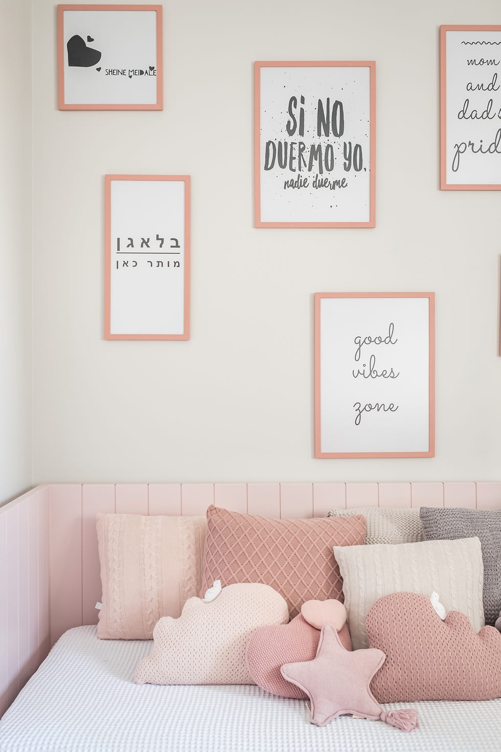 cama infantil con cojines rosas e ilustraciones en la pared