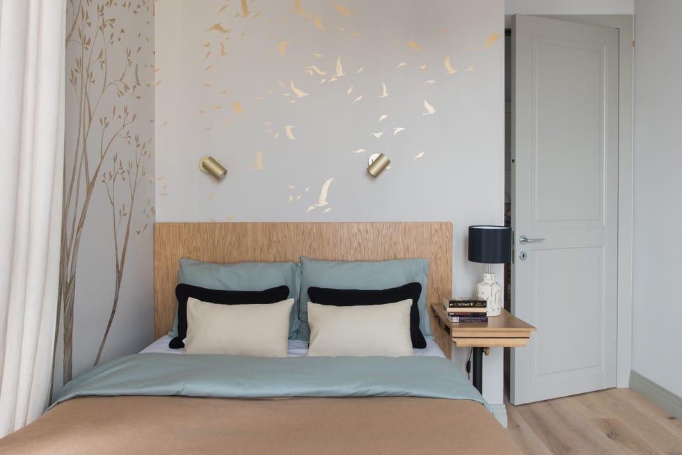 dormitorio con mural con dibujos dorados de pájaros y cabecero de madera