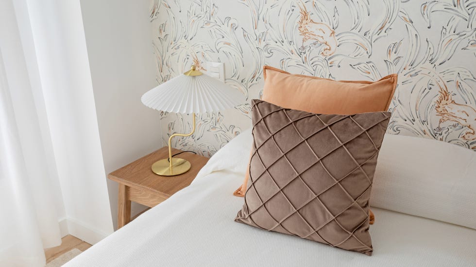 dormitorio con papel pintado con motivos florales y mesillas de madera