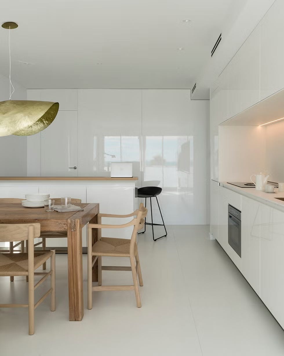 Modern kitchen and dining area with wooden dining table and white cabinetry