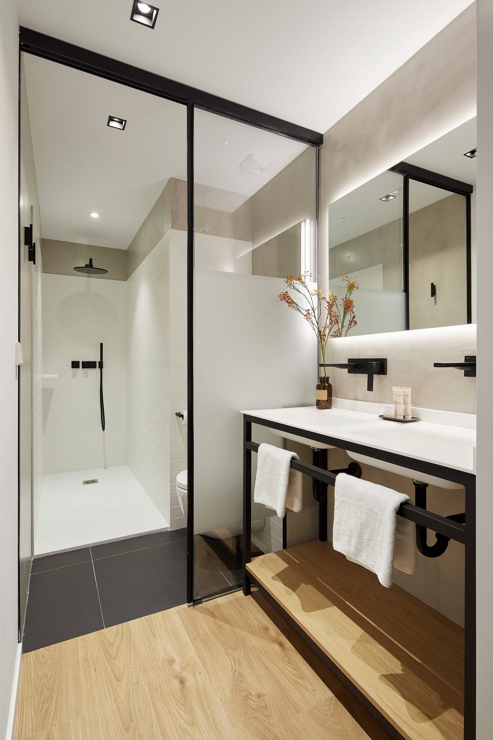 baño con ducha y mueble de lavabo de acero con balda de madera