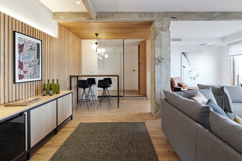 salón con pared de listones de madera y barra con taburetes