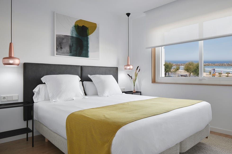 dormitorio con cabecero gris y vistas al mar