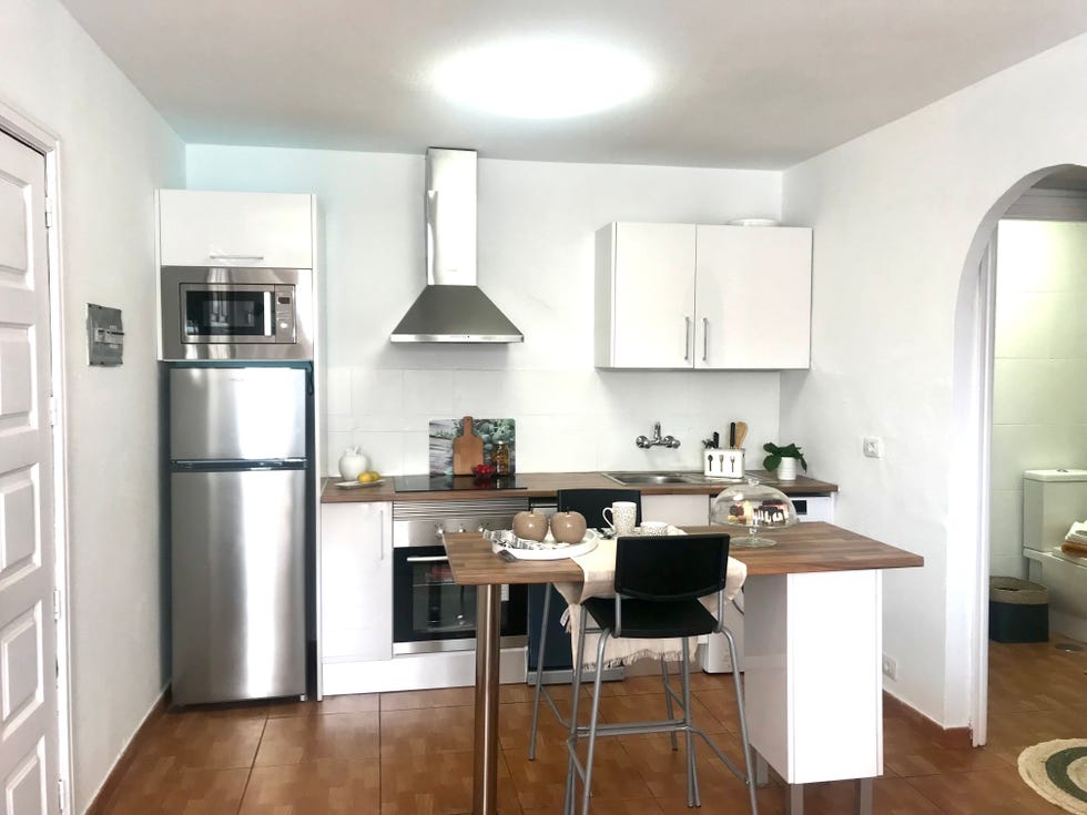 cocina blanca abierta con isla central y encimera de madera