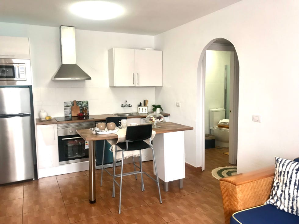 cocina blanca abierta con isla central y encimera de madera