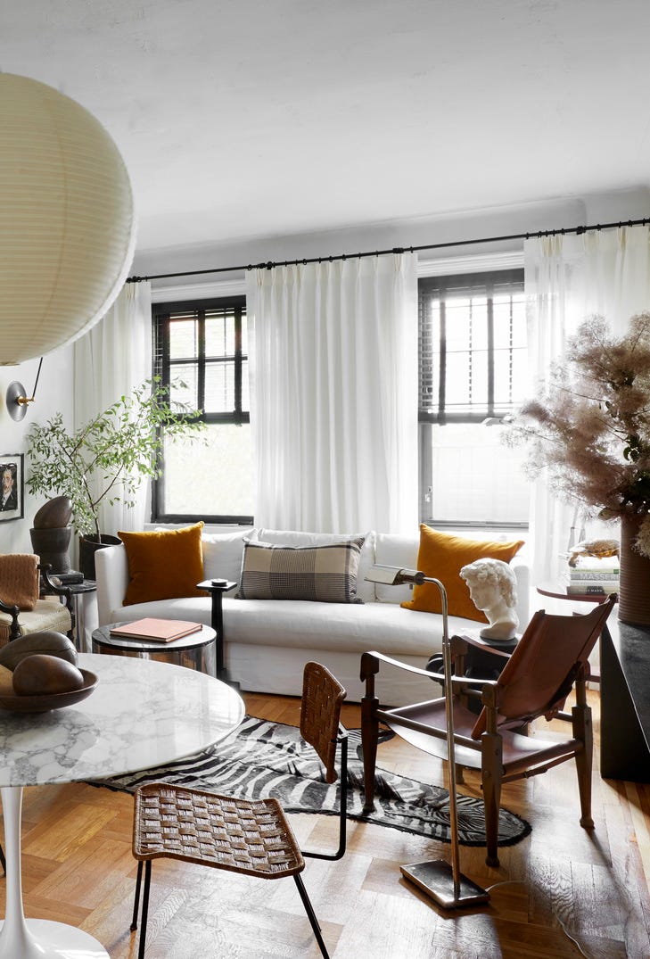 david frazier nyc apartment living room with limited space in this new york city apartment, designer david frazier divided the living room into two distinct zones lounging and eating paint simply white, benjamin moore dining table eero saarinen, knoll chairs lee industries slipper vintage french rattan vintage kaare klint safari pendant isamu noguchi bookcase scott antique markets ram’s head vintage, high point market