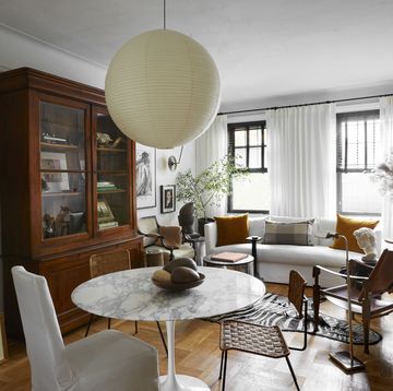 david frazier nyc apartment living room with limited space in this new york city apartment, designer david frazier divided the living room into two distinct zones lounging and eating paint simply white, benjamin moore dining table eero saarinen, knoll chairs lee industries slipper vintage french rattan vintage kaare klint safari pendant isamu noguchi bookcase scott antique markets ram’s head vintage, high point market