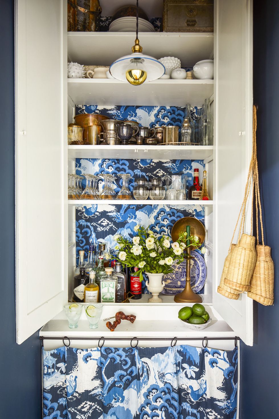 chicago, il apartment of devin kirk, vp of merchandising at jayson home pantry bar wall paint hague blue, farrow  ball fabric road to canton, robert allen light vintage enamel from france glassware vintage and beldi from jayson home