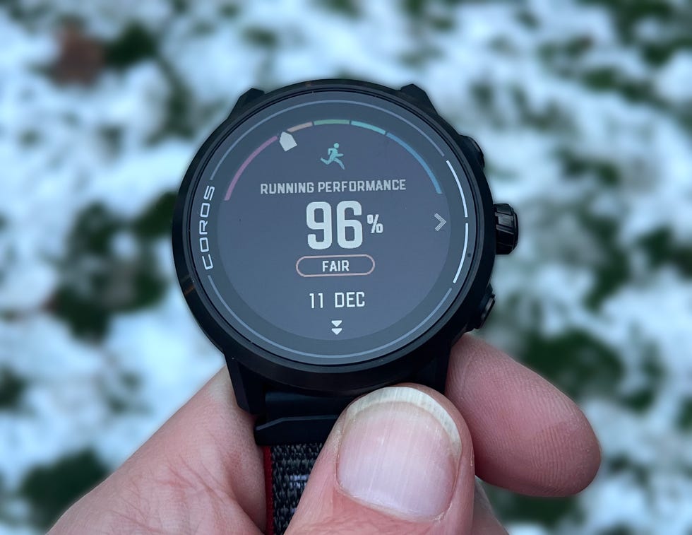 Hand holding a running watch showing a percentage of mileage