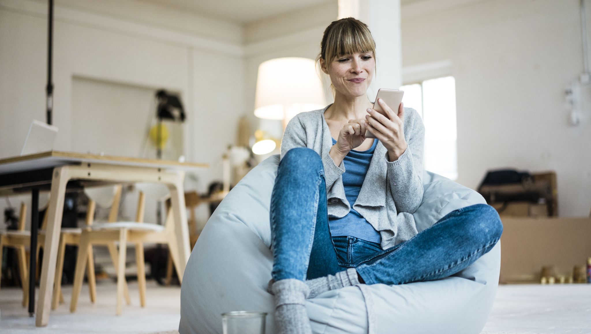 Smiling woman sitting in beanbag using cell phone
