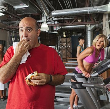 hombre poco en forma comiendo un bocadillo en un gimnasio