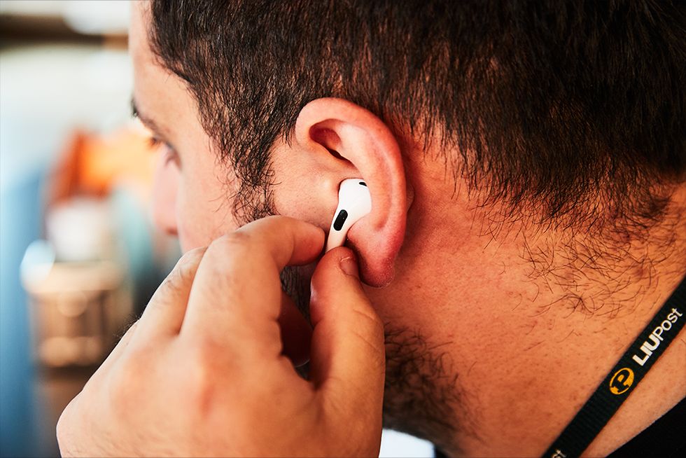 apple air pod 2nd generation in our test editors ear with him playing with touch controls