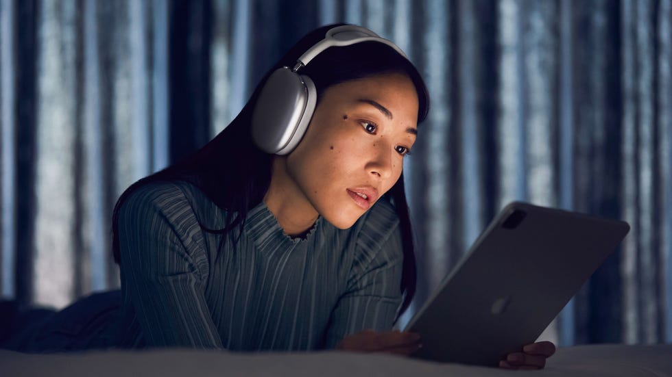 person using a tablet while wearing headphones in a dimly lit environment