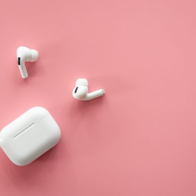 wireless in ear headphones with a case on a pink background, flat lay, conceptual minimalism