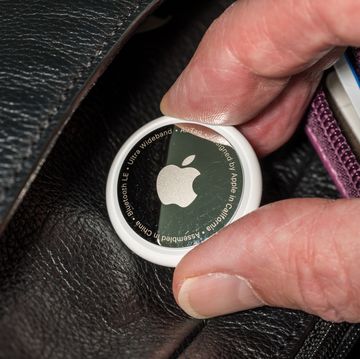 apple airtag being inserted into a leather compartment