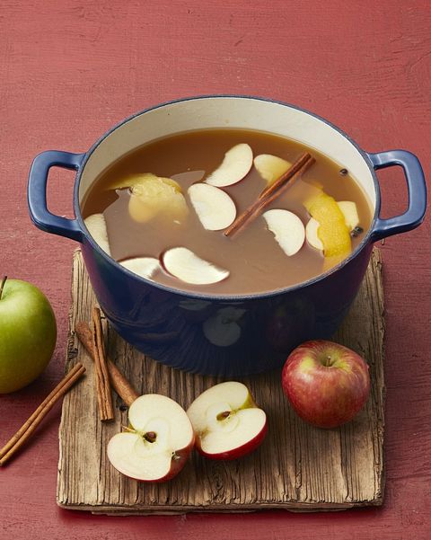 mulled apple cider in blue pot with apples and cinnamon sticks