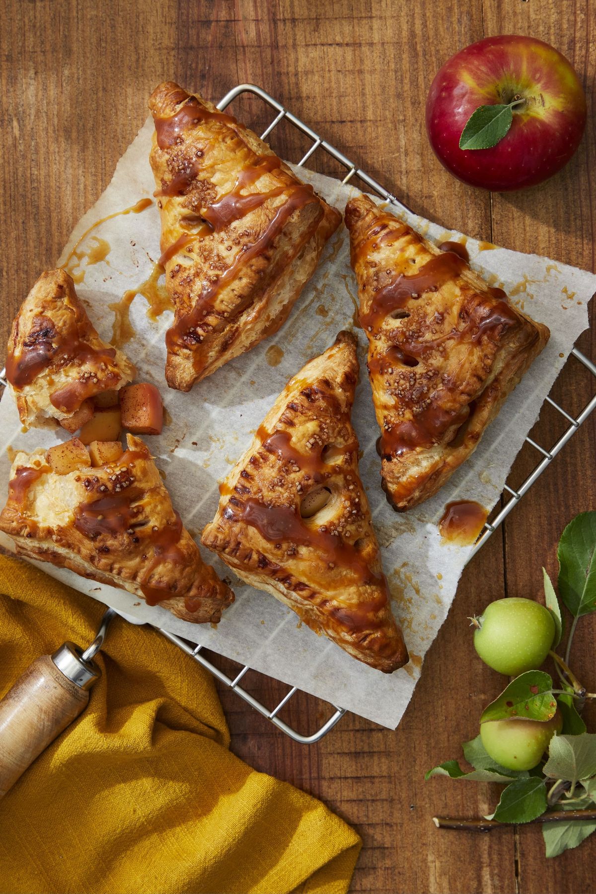 caramel apple turnovers on a parchment lined rack and drizzled with caramel