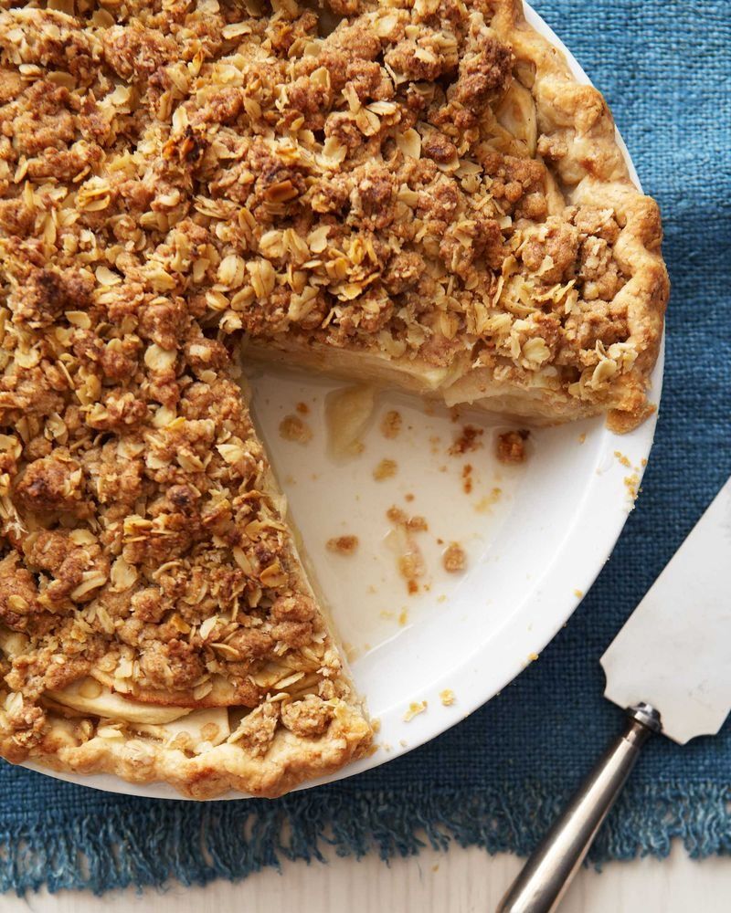 apple cheddar crumble pie in a white pie plate with a slice removed