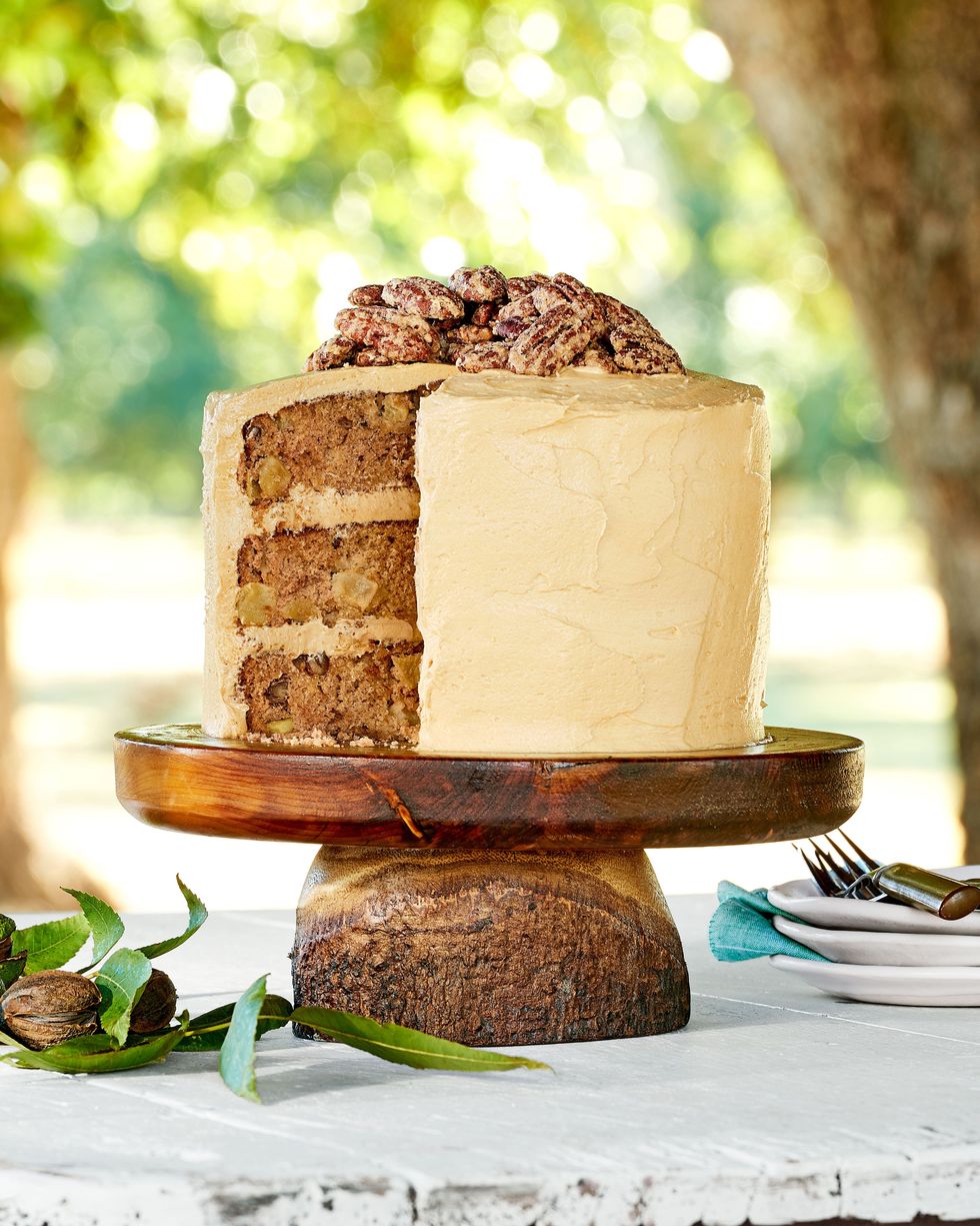 apple cinnamon layer cake on a wooden cake stand on a white wooden table outside