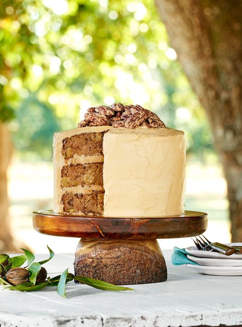 apple cinnamon layer cake on a wooden cake stand on a white wooden table outside