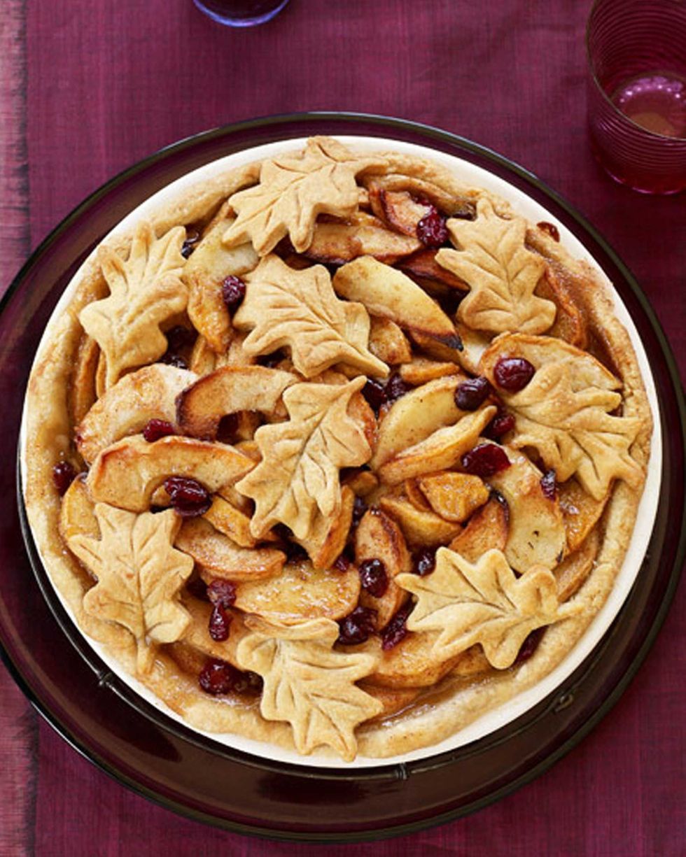 apple cranberry pie in a white pie plate with pie crust leaves on top