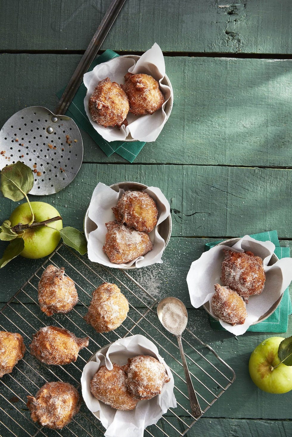 pie spiced apple fritters on a wire rack and some in parchment lined bowls