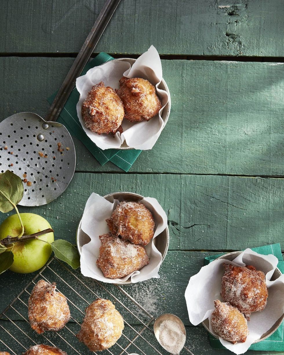 pie spiced apple fritters on a wire rack and some in parchment lined bowls