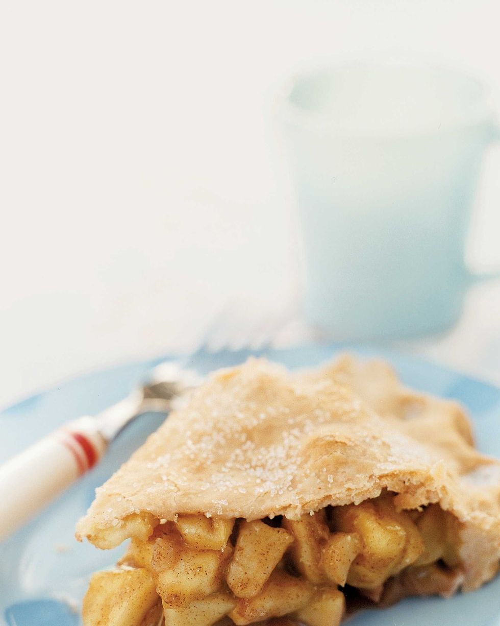 a slice of double crust apple pie on a light blue plate with a fork