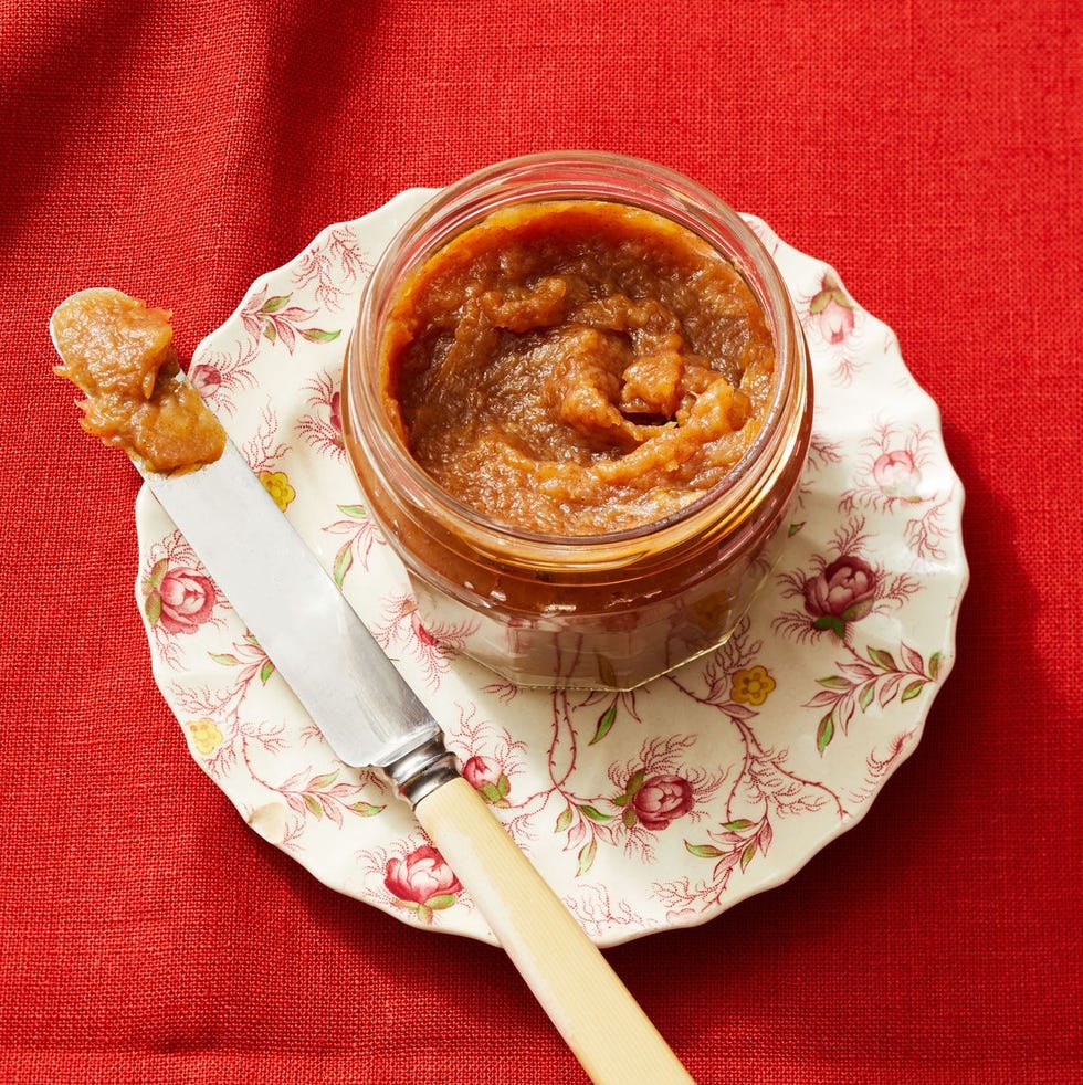 apple butter in a glass jar with butter knife on the side