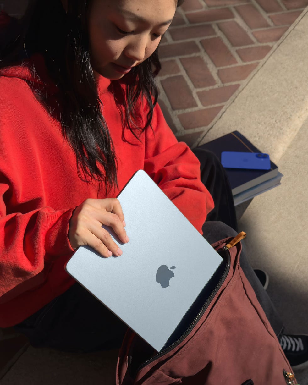 Der Laptop wird von einer Person mit einem im Kontext sichtbaren Rucksack behandelt