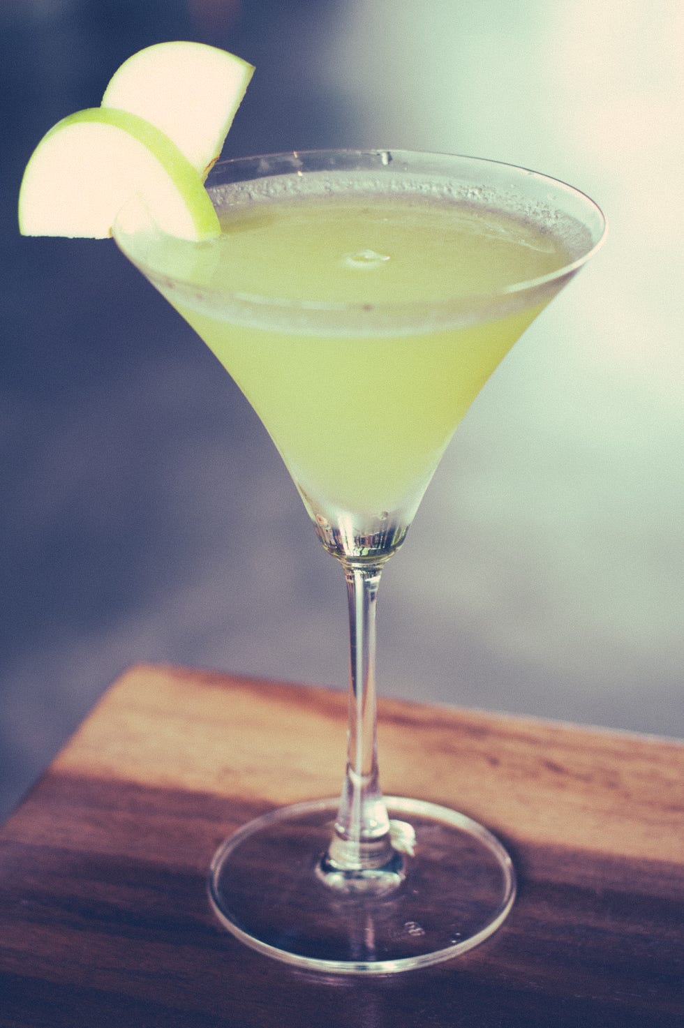 a green apple martini with green apple slices as garnish
