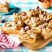 apple pie bars with walnuts on wooden board with parchment paper and red striped tea towel