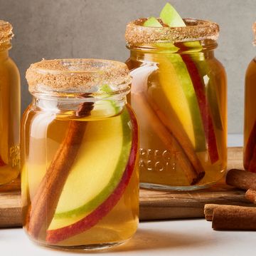 apple pie bourbon shots with apple slices and cinnamon sticks in little mason jars