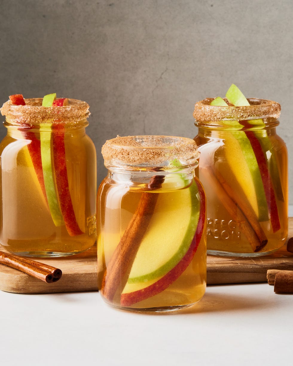 apple pie bourbon shots with apple slices and cinnamon sticks in little mason jars