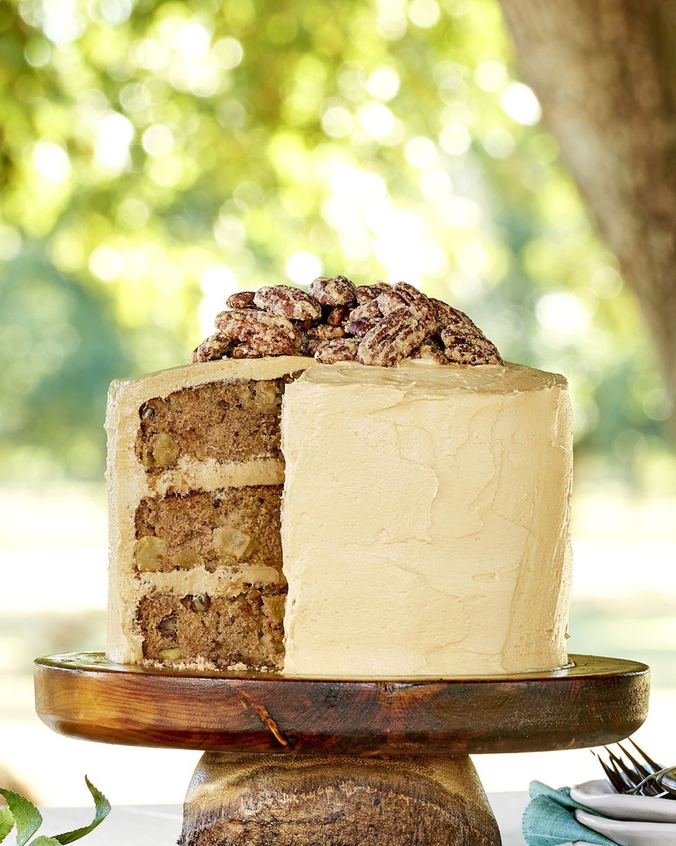 apple layer cake on a wooden cake stand with salted caramel frosting and candied pecans on top