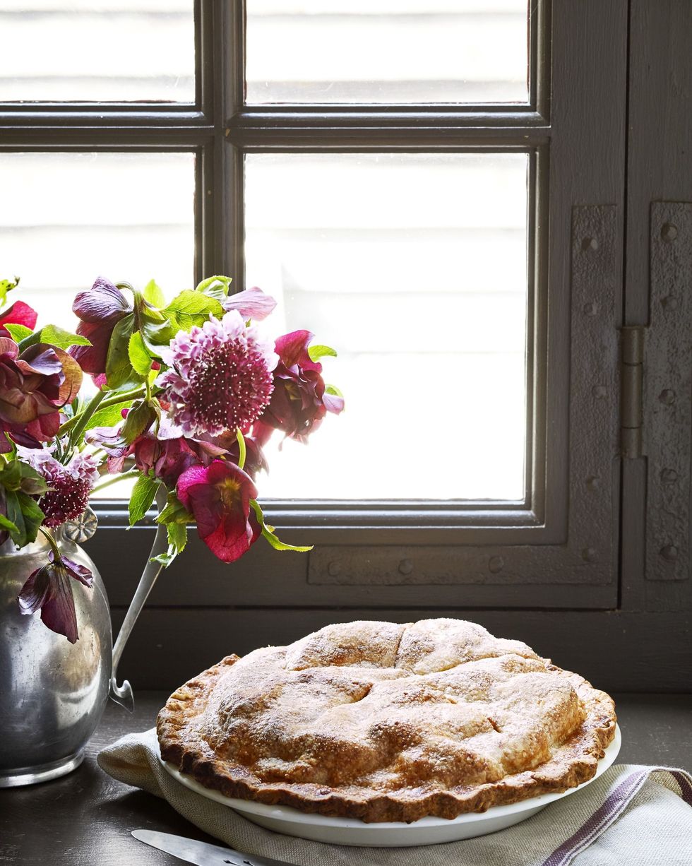 double crust apple cheddar pie on a window sill with a pie server