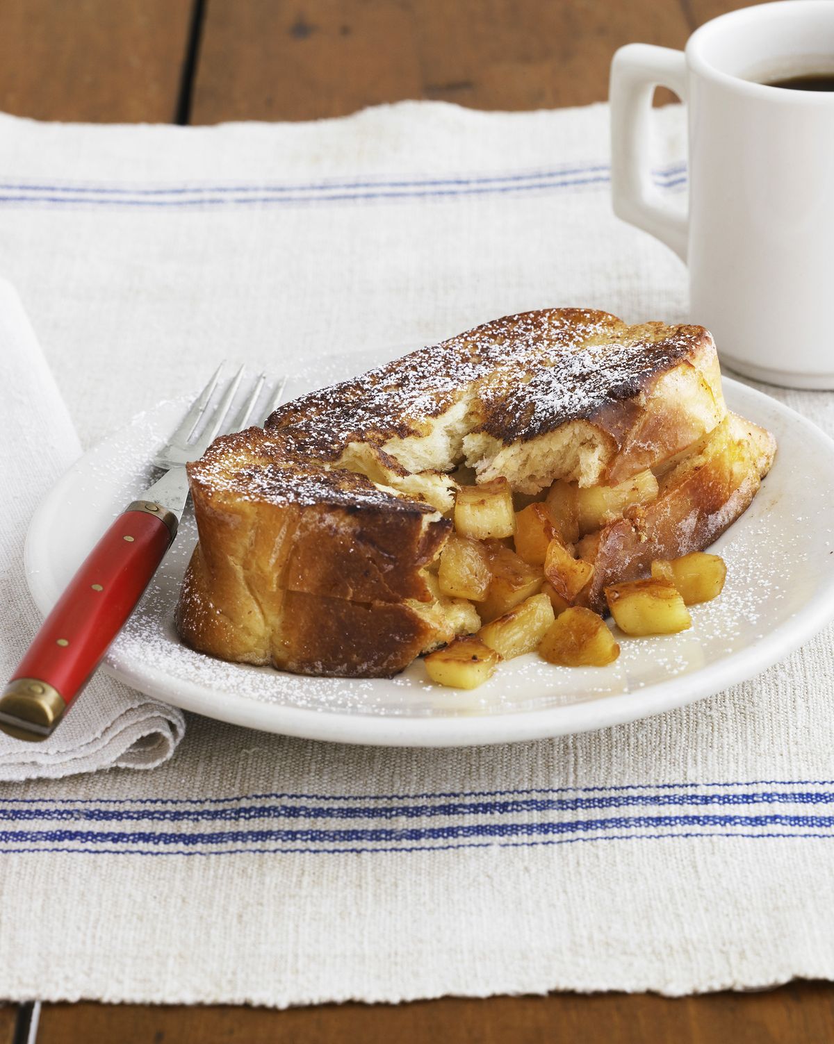 a plate of french toast with a fork and a cup of coffee