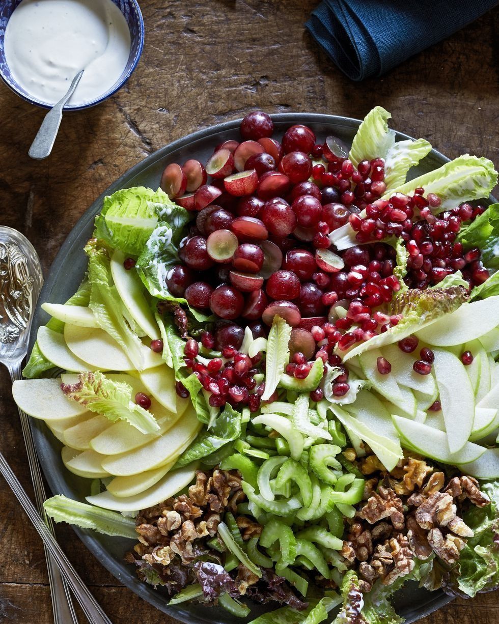 a bowl of composed waldorf salad with serving utensils on the side