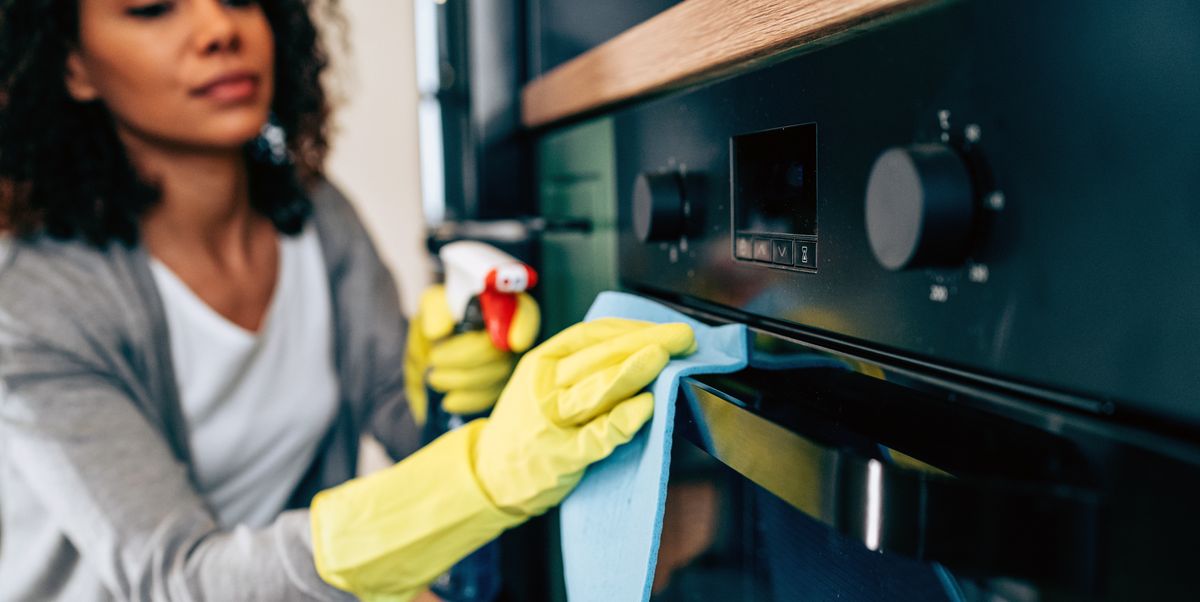 woman cleaning oven in yellow rubber gloves