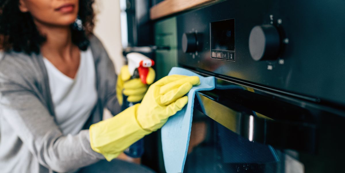 woman cleaning oven in yellow rubber gloves