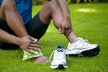 man in sportkleding koelt zijn pijnlijke enkel