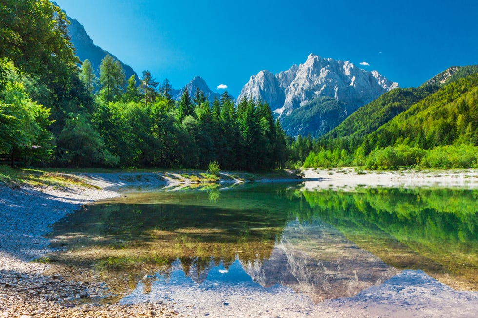 valley with the lake in the triglav national park the water surface reflects the surrounding mountains in julian alps , slovenia