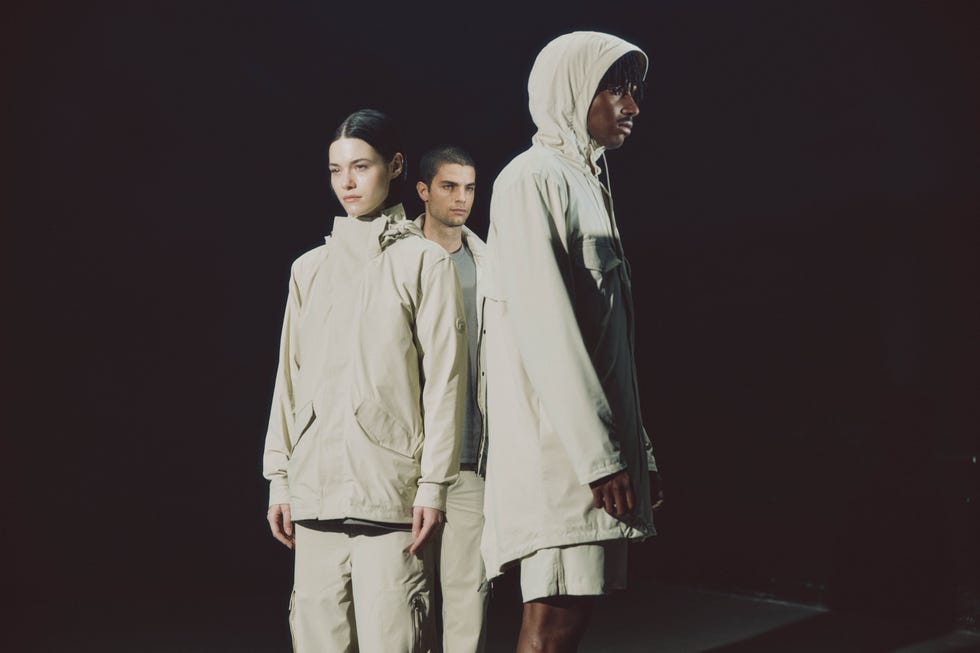 fashion models showcasing beige outerwear in a dimly lit setting