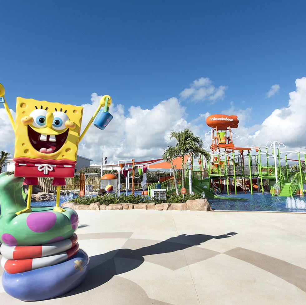 a statue of spongebob stands in front of the pool area at the nickelodeon hotel and resorts a good housekeeping pick for best all inclusive family resorts