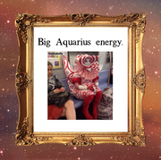 a photo of a person in a weird red and white costume sitting on the subway, labeled "big aquarius energy"