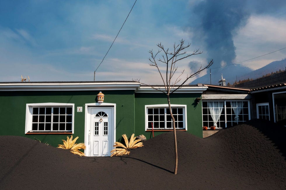 https://i.natgeofe.com/n/a7f5291a-dadf-4ae6-8f0b-0d46bb73f894/AR-volcano079.jpg Een huis in de wijk Las Manchas op La Palma is bedekt met vulkanische as die uit steen en glasscherven bestaat As kan zo zwaar worden dat de daken van huizen kunnen instorten Hierdoor moeten veel eilandbewoners hun huizen stutten met houten palen Uit Dramatische fotos tonen de voortdurende uitbarsting van de vulkaan van La Palma november 2021