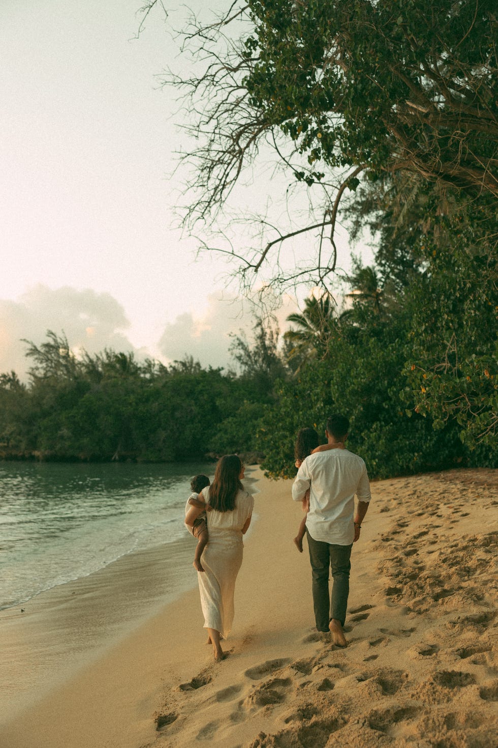 family of four walking along beach in hawaii